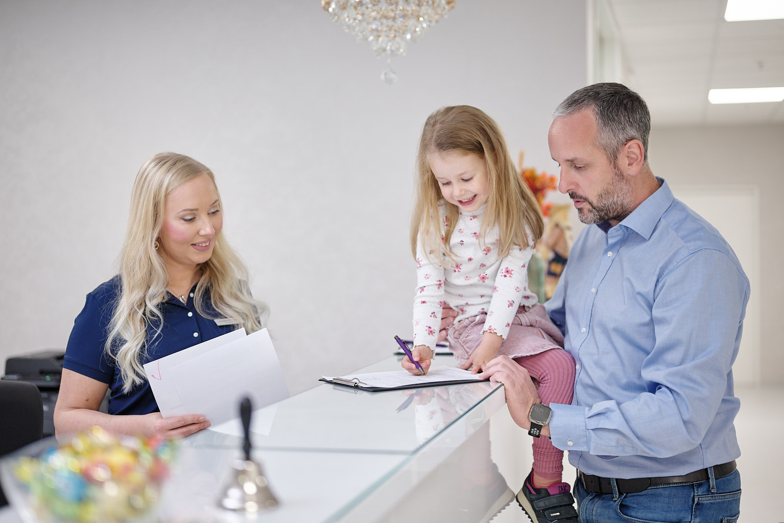 Familie bei der Anmeldung am Empfang der Kinderarztpraxis Chur West